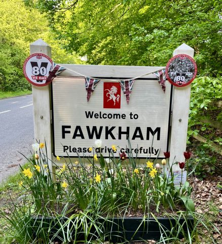 Welcome to Fawkham sign with Union Jack bunting and VE Day 80 signs