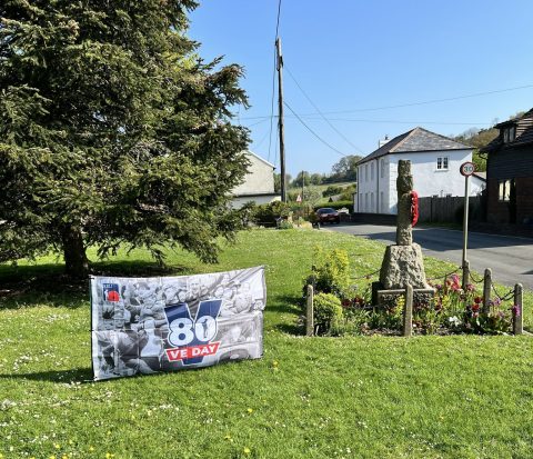 village green with. VE Day 80 flag and war memorial